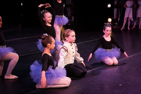 children sitting on dance stage