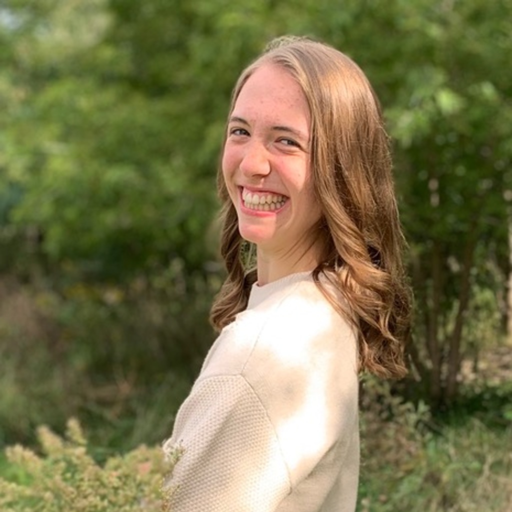 Martha Hamilton smiling and holding wildflowers outdoors