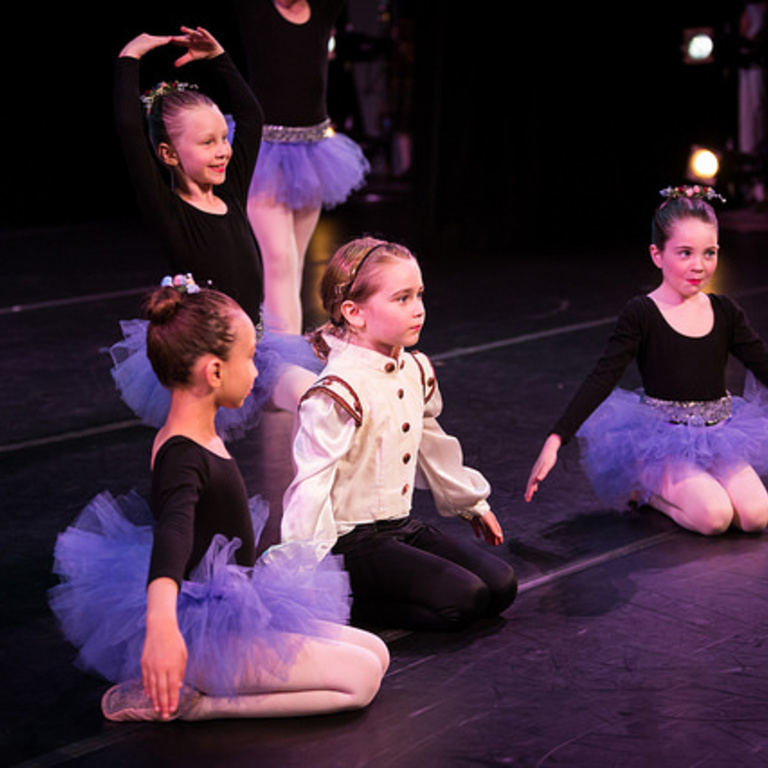 children sitting on dance stage
