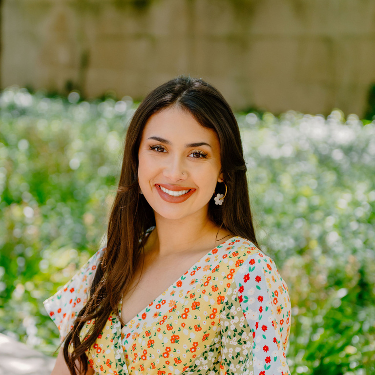 Ellie Daley seated outdoors, smiling in a floral-print dress