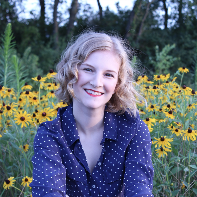Paige Waller smiling seated in front of a field of black-eyed Susans.