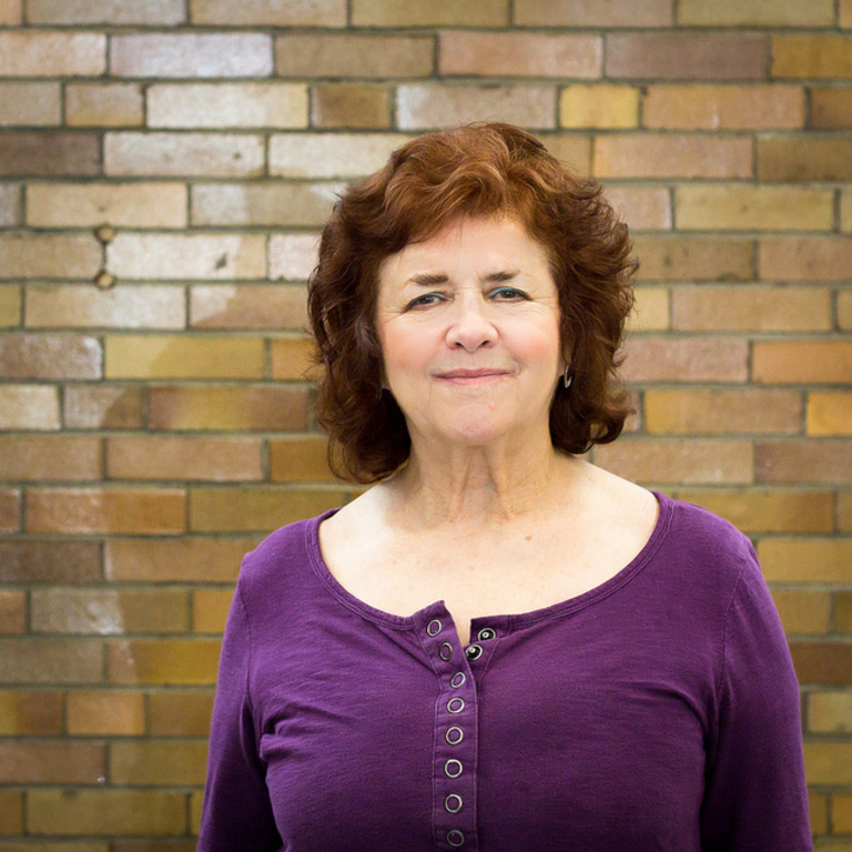 Joan Gonwa stands smiling against a brick background of Halsey Hall